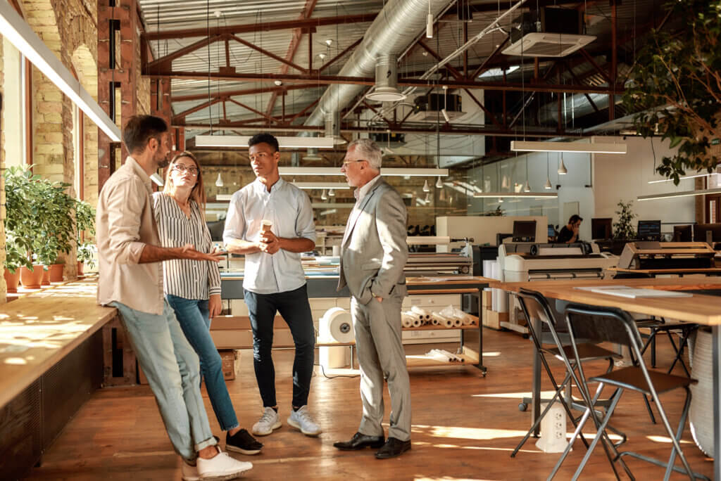 Fast meeting. Business people holding coffee cups and talking about something while standing in the modern office. Coffee break. Teamwork