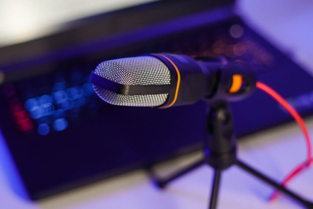 Mikrofon und Laptop für die Aufnahme eines Live-Streams über einem blauen Hintergrund. Von Dolmetscher unterstützt
